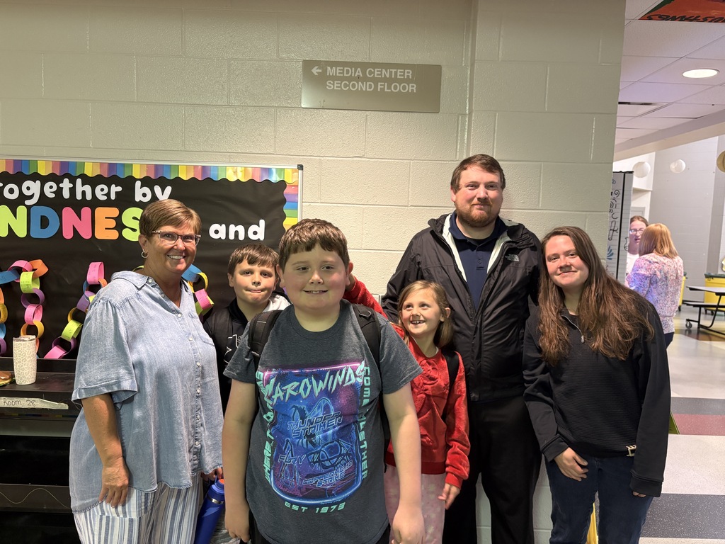 Student posing with their family members and teacher