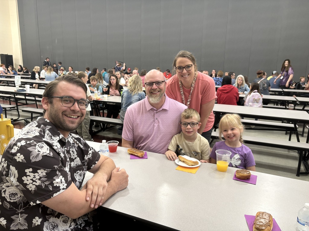 Student posing with their family members and teacher