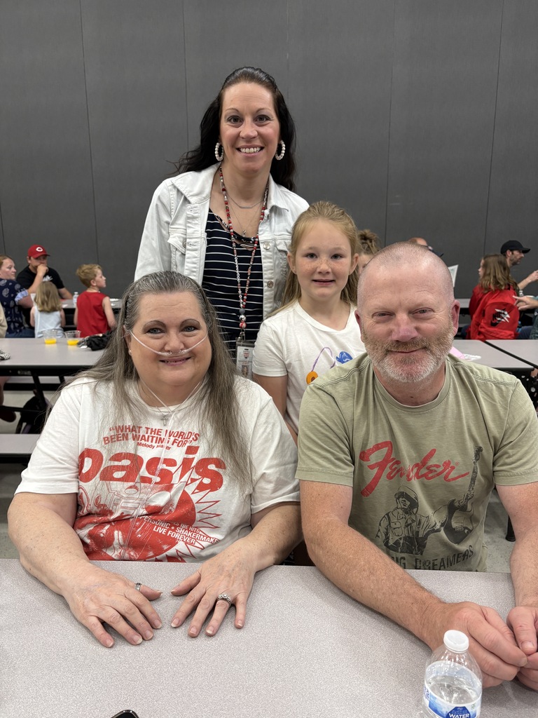 Student posing with their family members and teacher