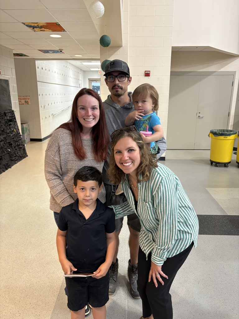Student posing with their family members and teacher