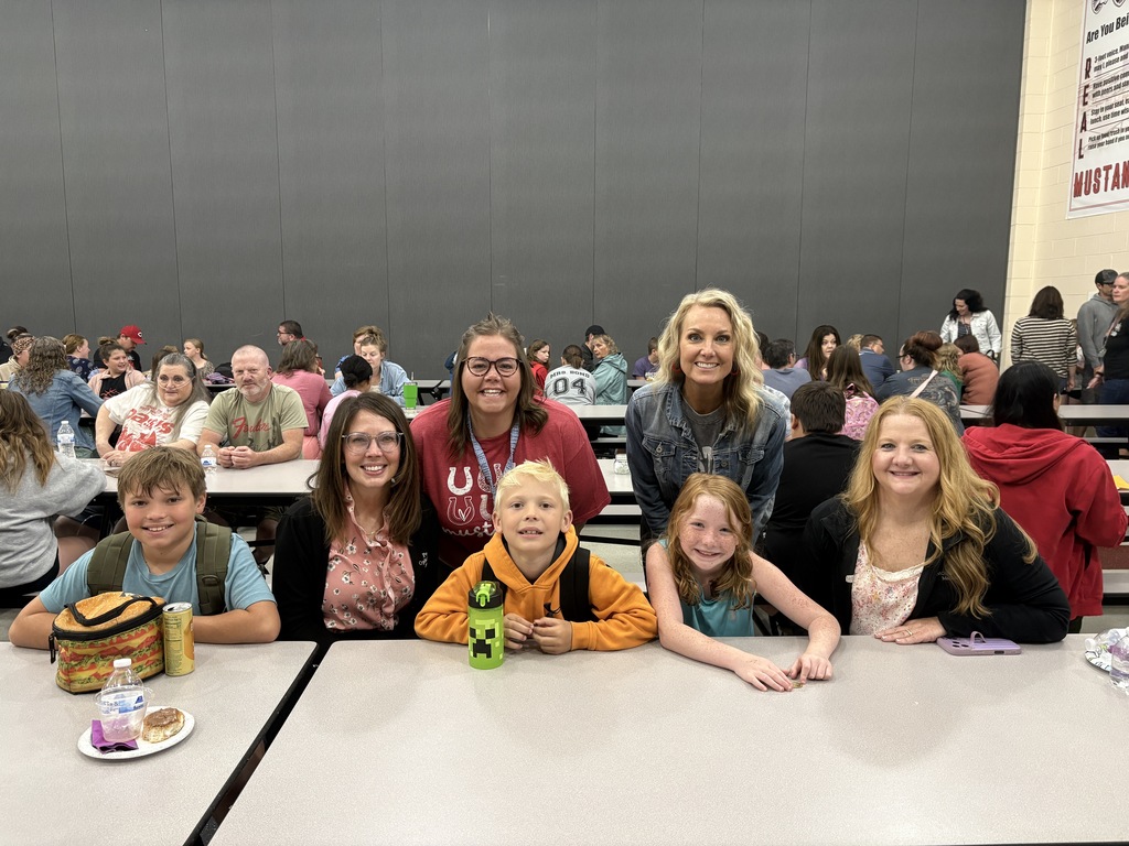 Student posing with their family members and teacher