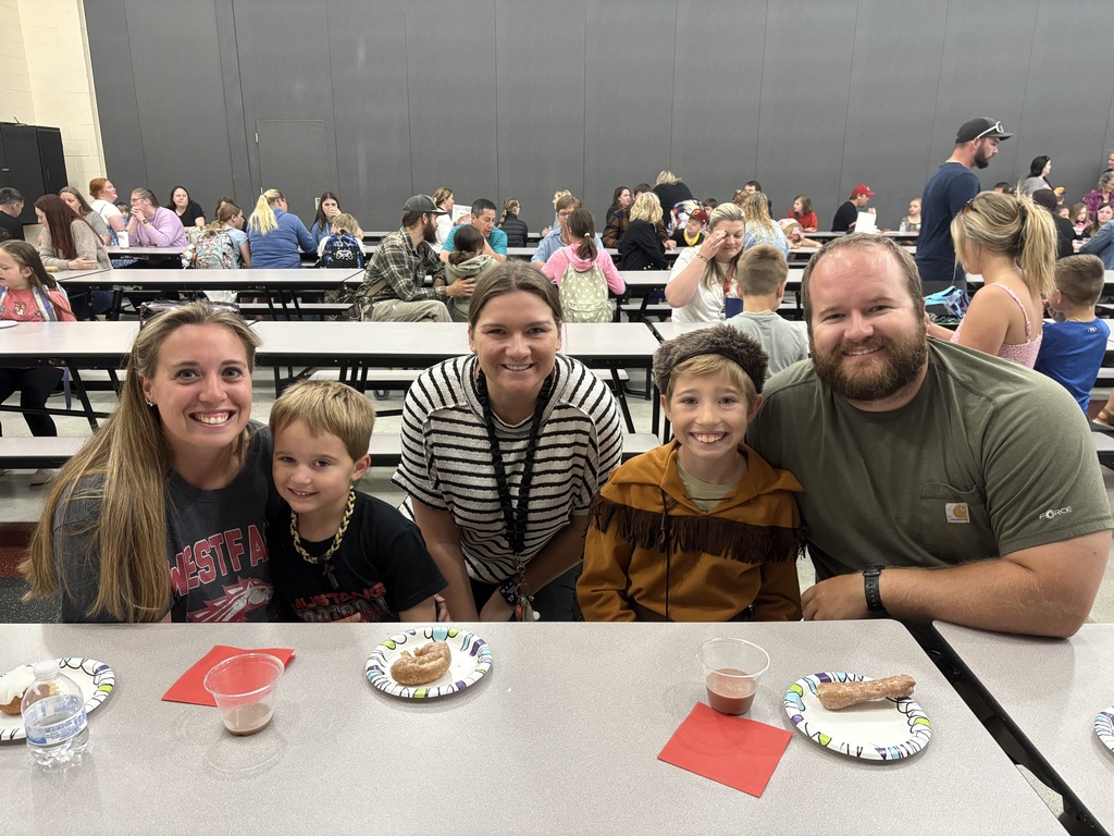 Student posing with their family members and teacher
