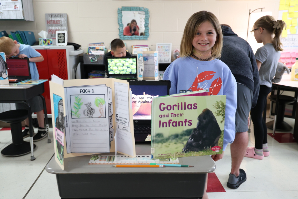 Student posing with their animal research project and Johnny Appleseed PowerPoint presentation