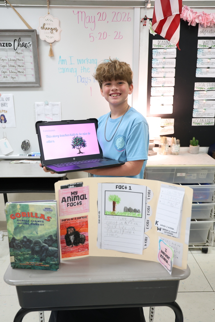 Student posing with their animal research project and Johnny Appleseed PowerPoint presentation