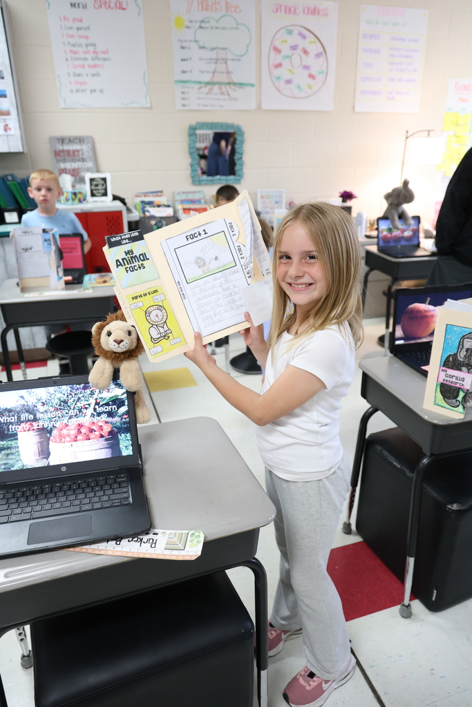 Student posing with their animal research project and Johnny Appleseed PowerPoint presentation
