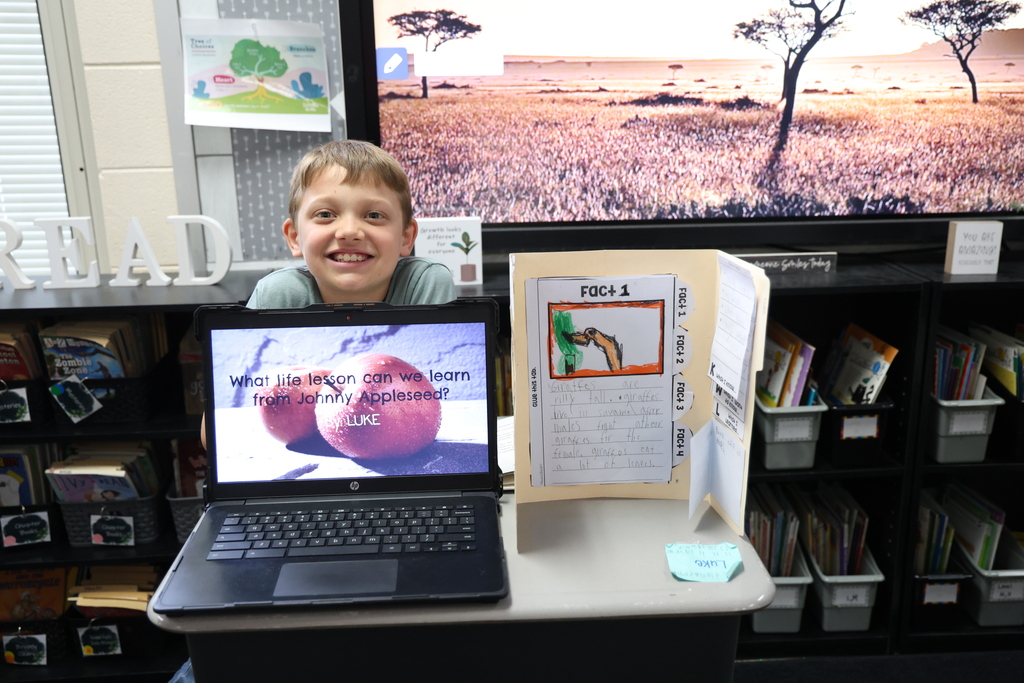 Student posing with their animal research project and Johnny Appleseed PowerPoint presentation