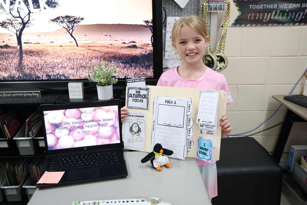 Student posing with their animal research project and Johnny Appleseed PowerPoint presentation
