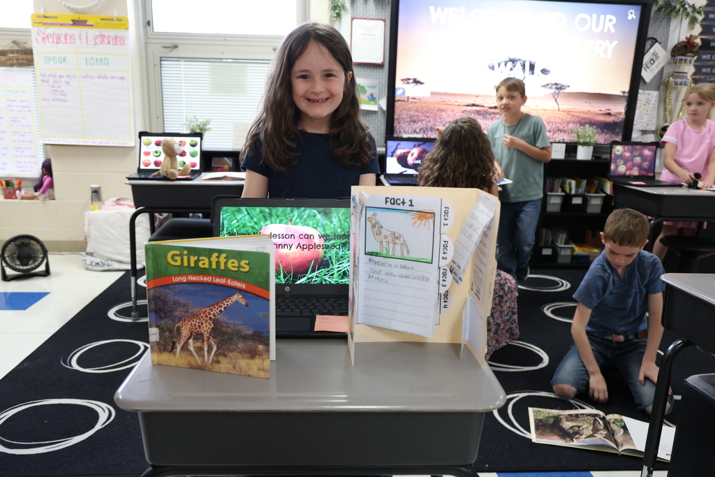 Student posing with their animal research project and Johnny Appleseed PowerPoint presentation
