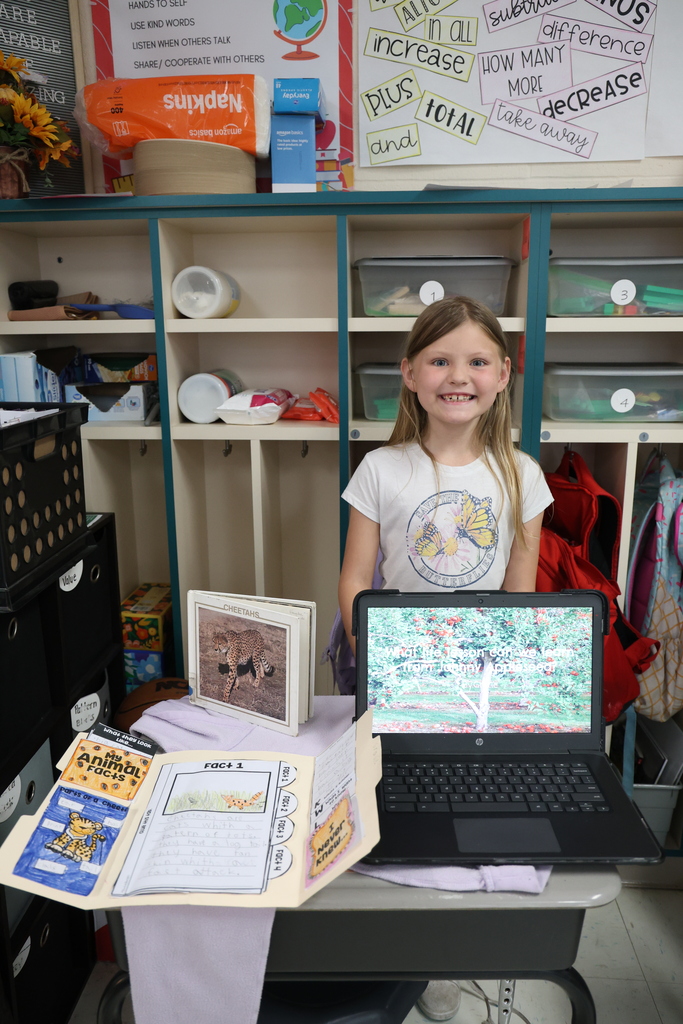 Student posing with their animal research project and Johnny Appleseed PowerPoint presentation