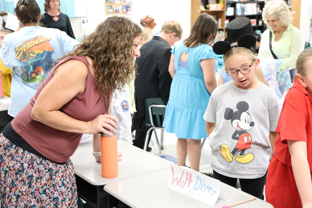 Student presenting her project dressed in Disney gear, posing as Walt Disney