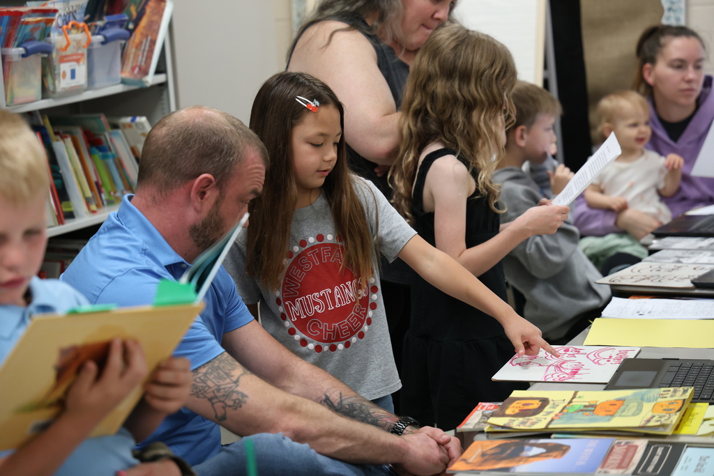 Students reading to their family members and guests