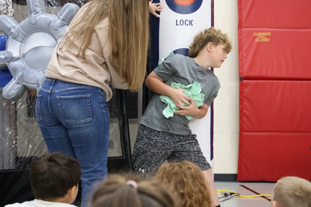 Student coming out of plastic money machine holding an arm's full of green paper