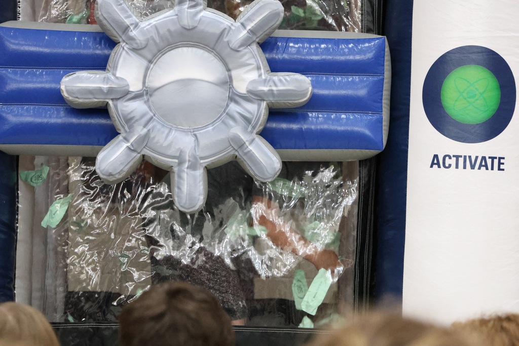 Student reaching for green paper in a plastic "money machine"