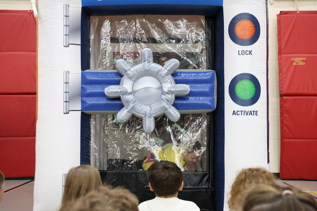 Student reaching for green paper in a plastic "money machine"