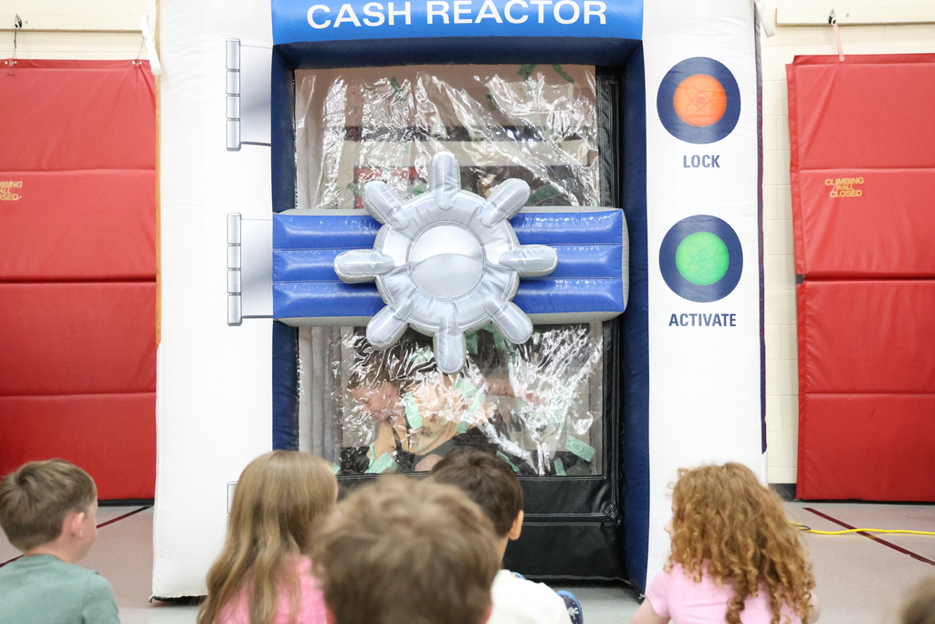 Student reaching for green paper in a plastic "money machine"