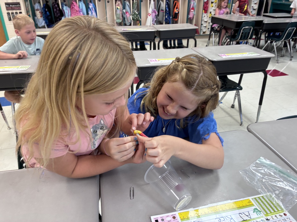 Students using paper clips to hold their gummy worm