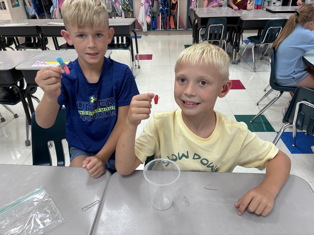 Students using paper clips to hold their gummy worm