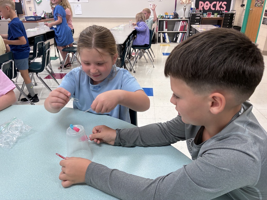 Students using paper clips to hold their gummy worm
