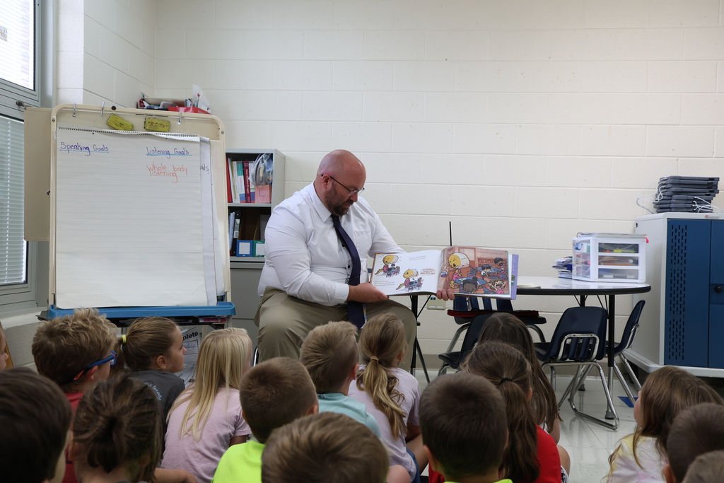 Mr. Pentiuk reading a storybook to a group of first grade students