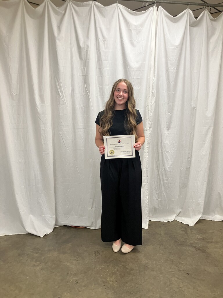 Lydia Colahan holding a certificate in front of a white backdrop