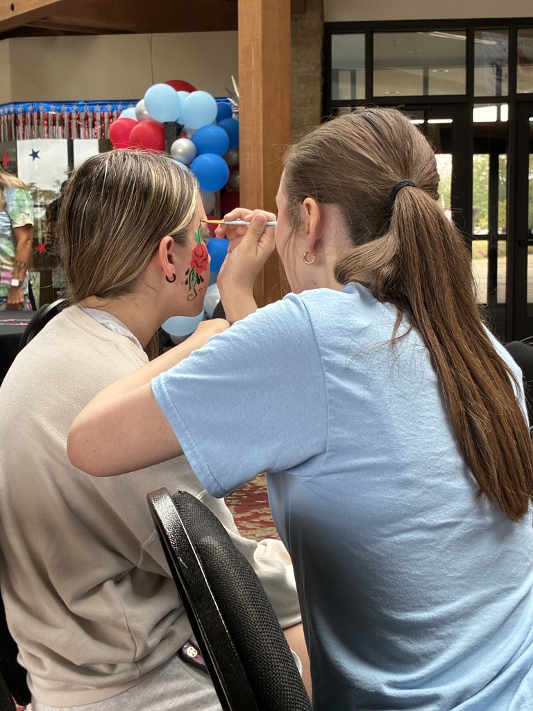 Student facepainting another student