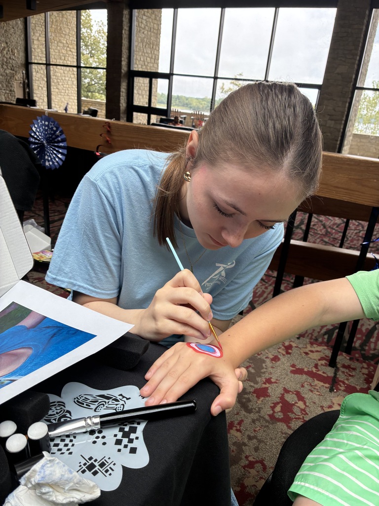 Student painting a Superhero shield onto a child's hand
