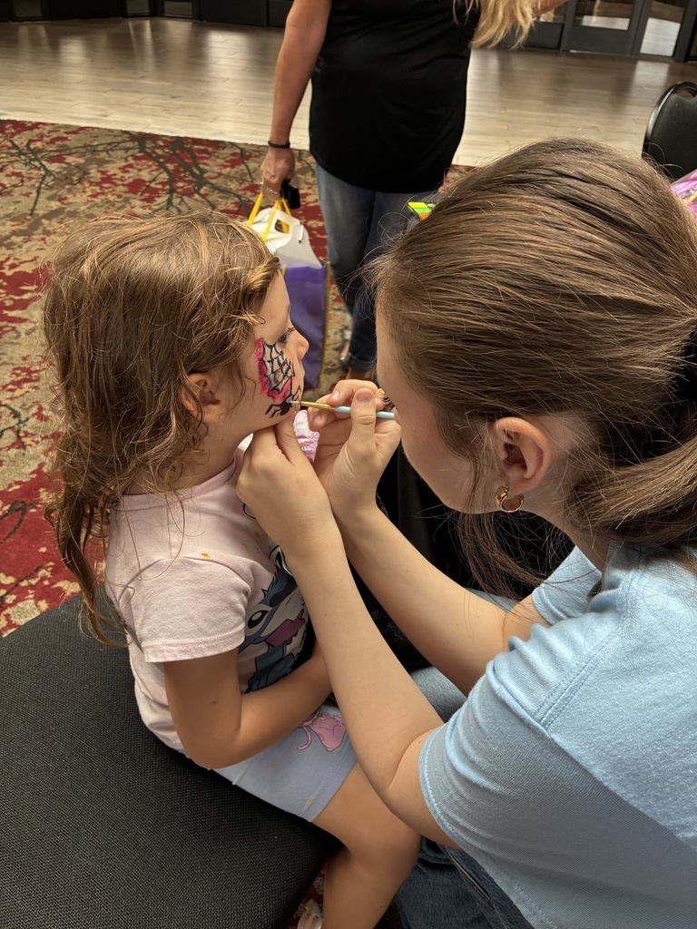 Student face painting a child