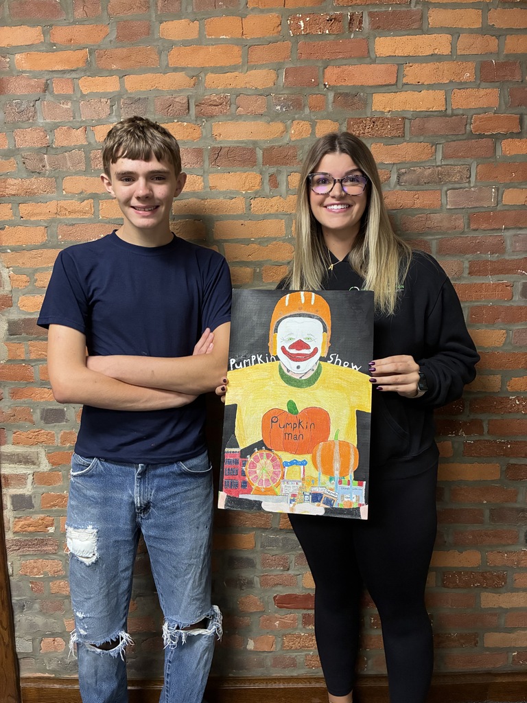 Haiden Hay with representative from Elite Construction holding Pumpkin Show artwork