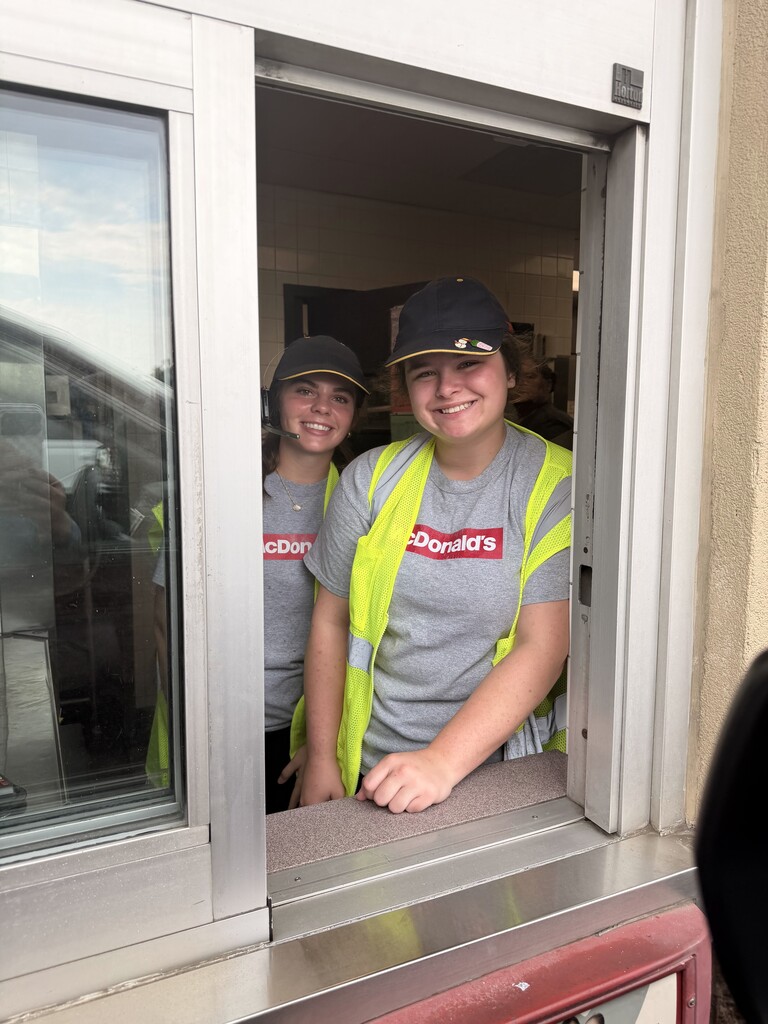 Photo of two students through a drivethru window wearing McDonald's tshirts