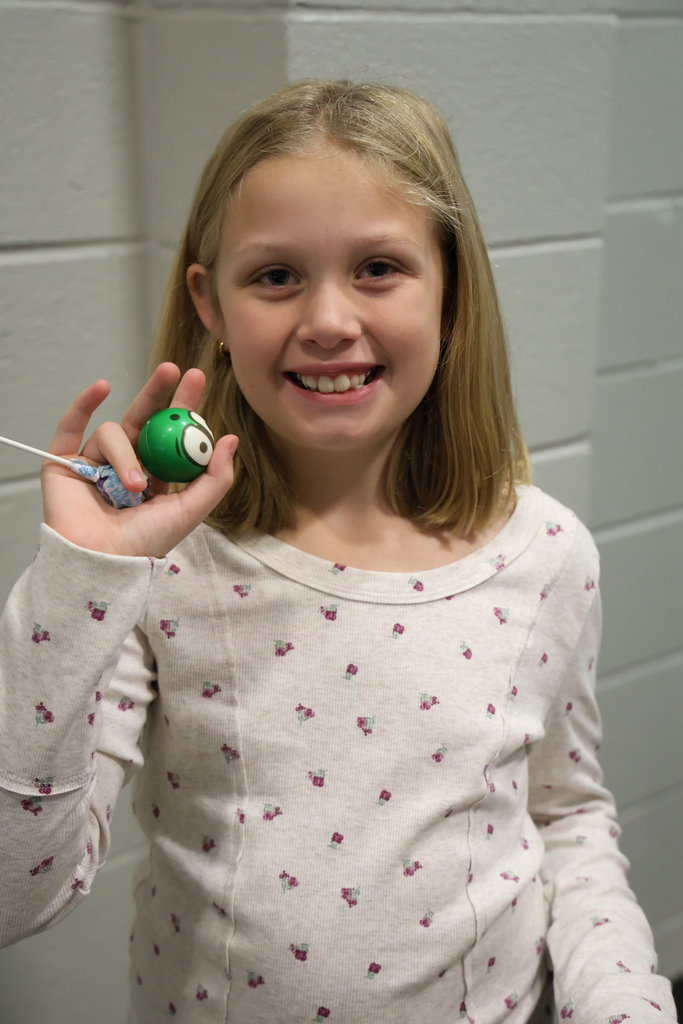 Student holding up a sucker and a smiley face squishy ball