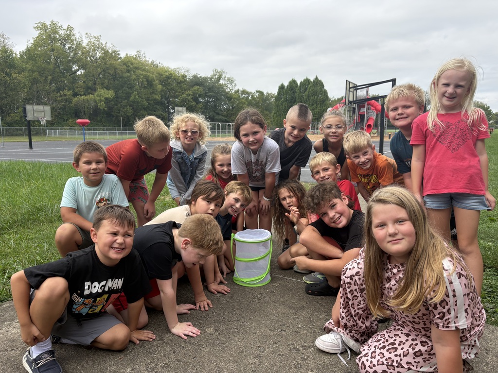 Students standing aroubnd net basket with butterfly inside