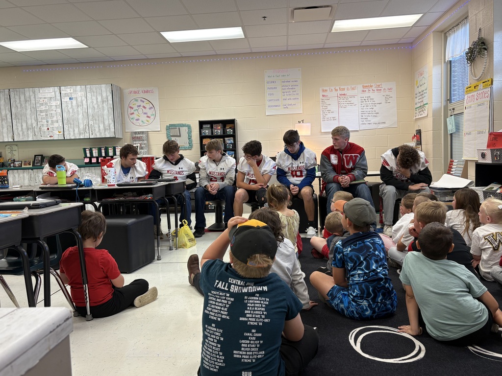 Football players reading to group of students