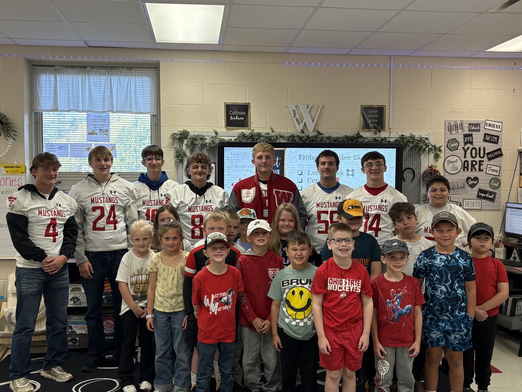 Football players posing with students