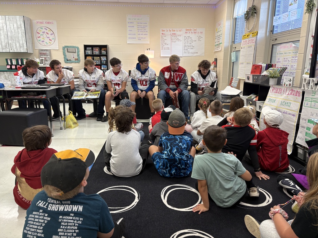 Football players reading to group of students