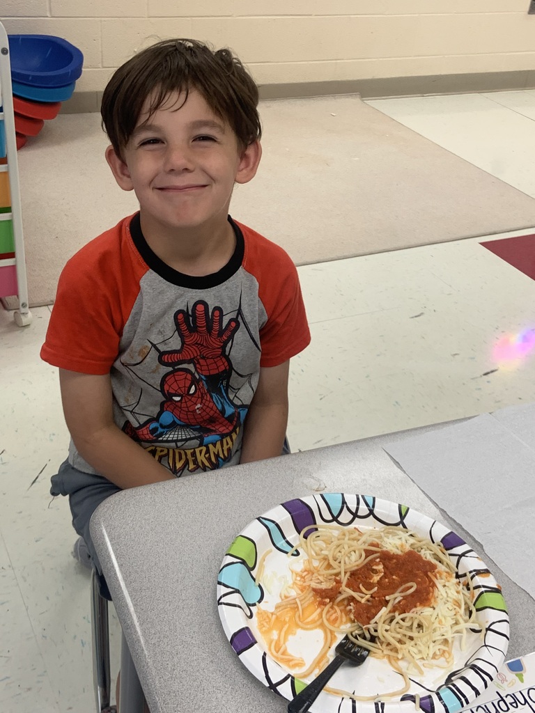 Student smiling in front of a plate of spaghetti