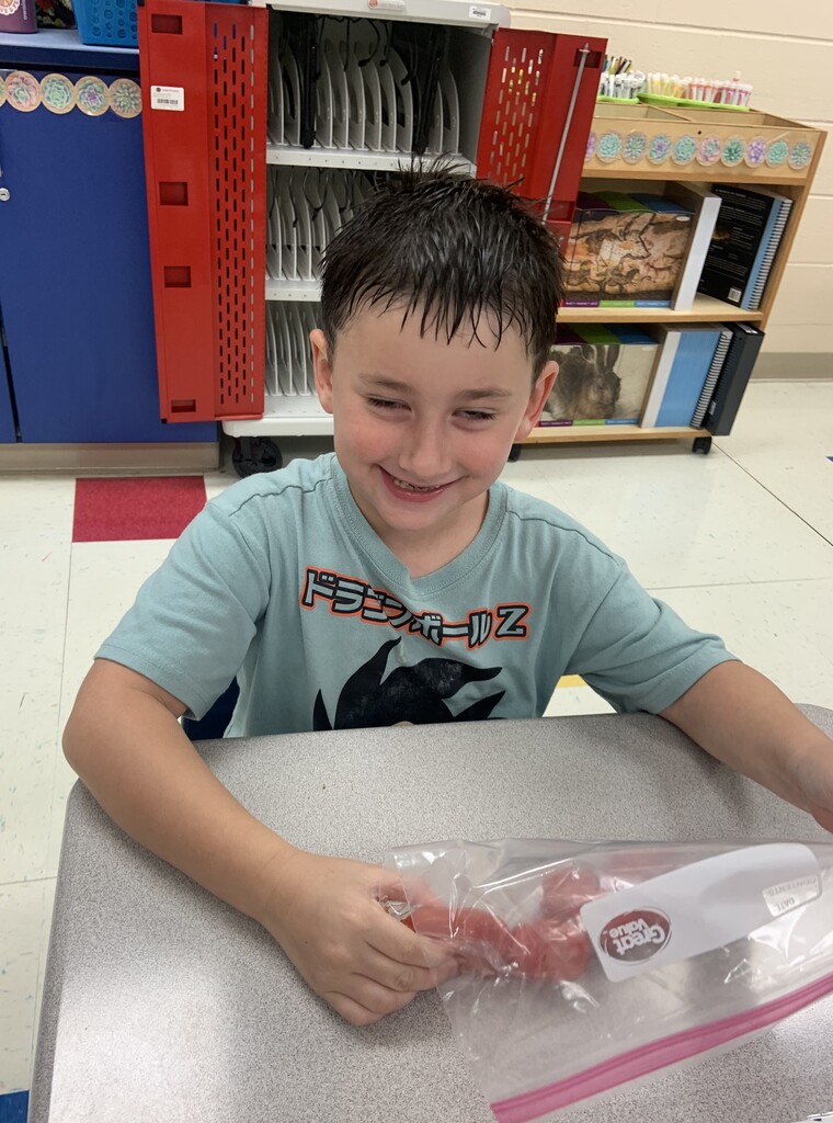 Student smiling while holding onto a ziploc bag full of tomatoes