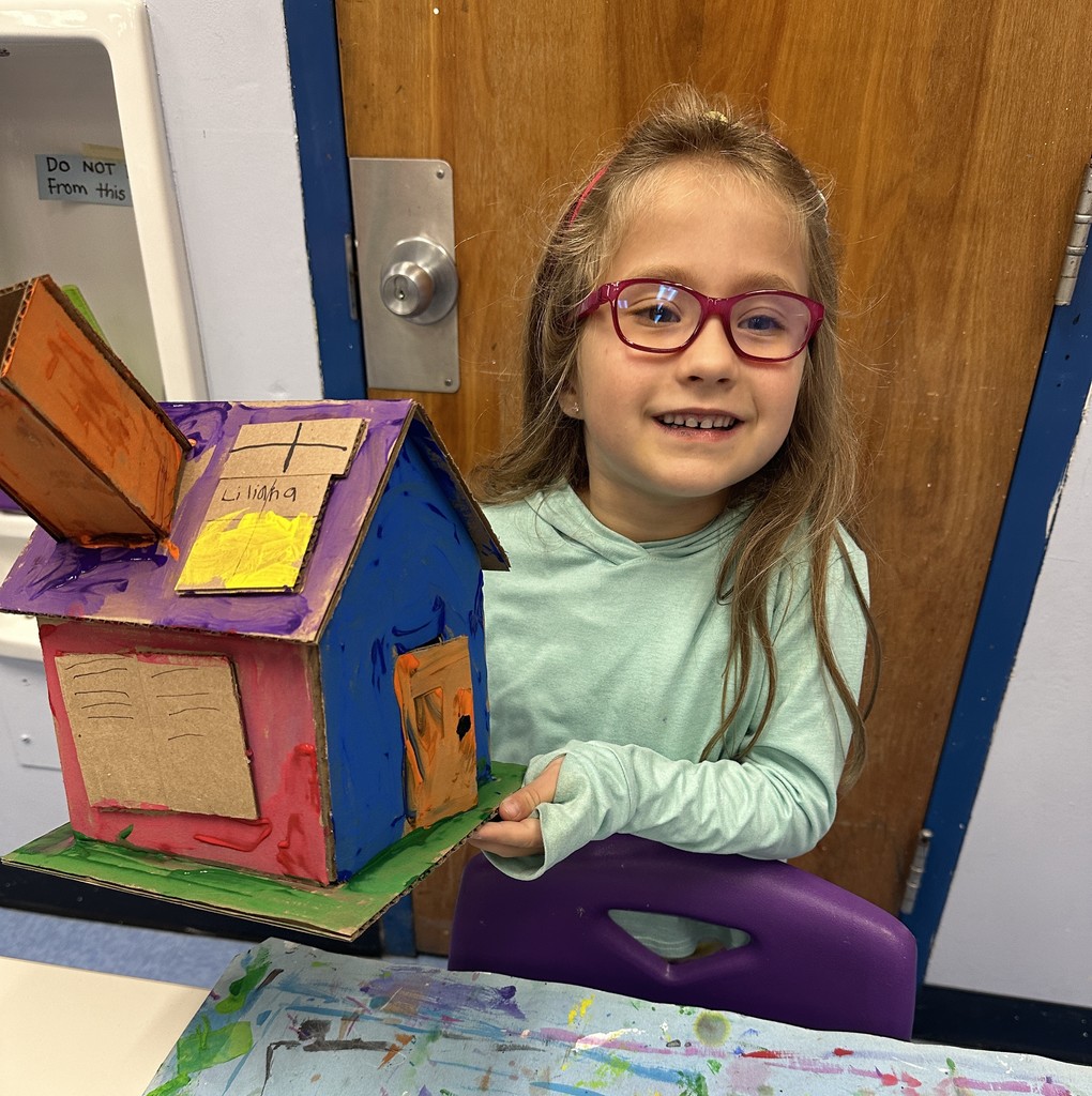 student holding up completed house