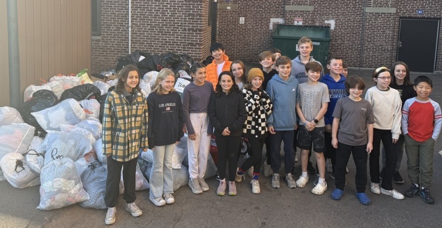 Group photo of McKinley students outside next to bags of donated clothing and coats