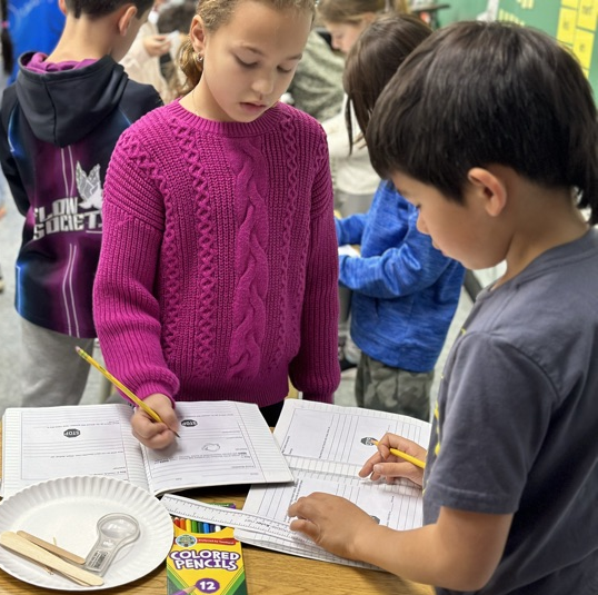 3rd graders write down observations in science journals