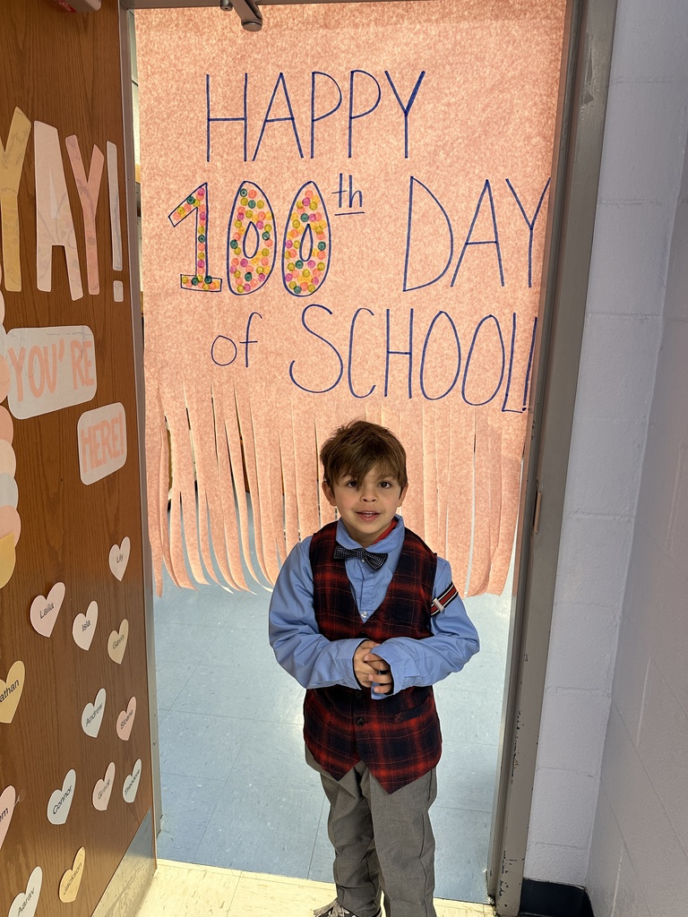 student standing in front of happy 100th day of school sign