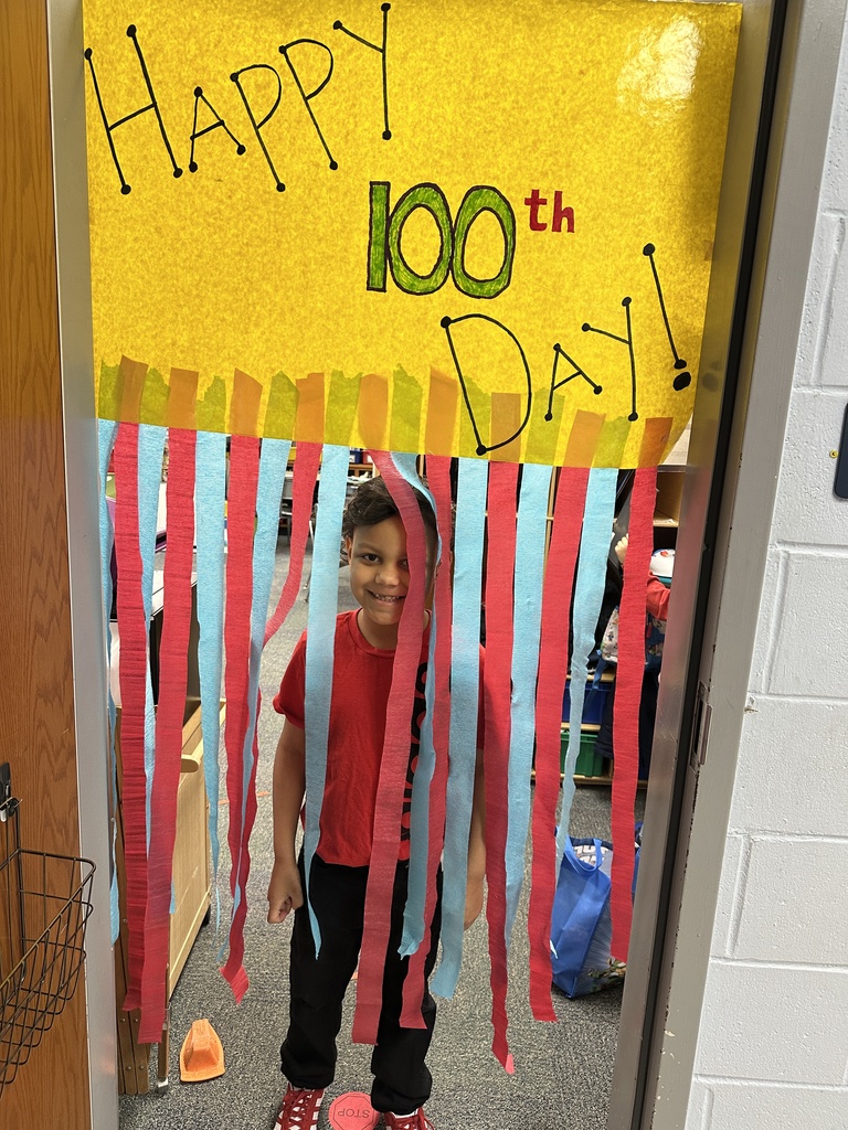 student standing in front of happy 100th day sign
