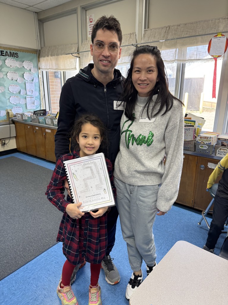 Student proudly shows her book to her parents.