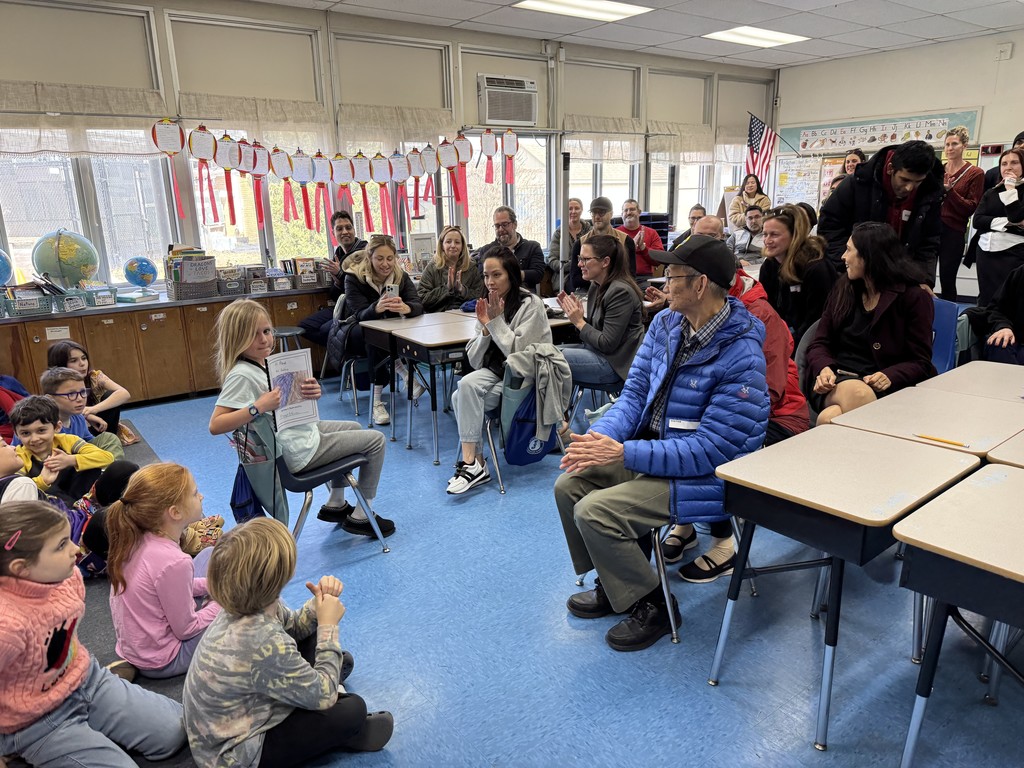 Student reading from her book to the adult audience.