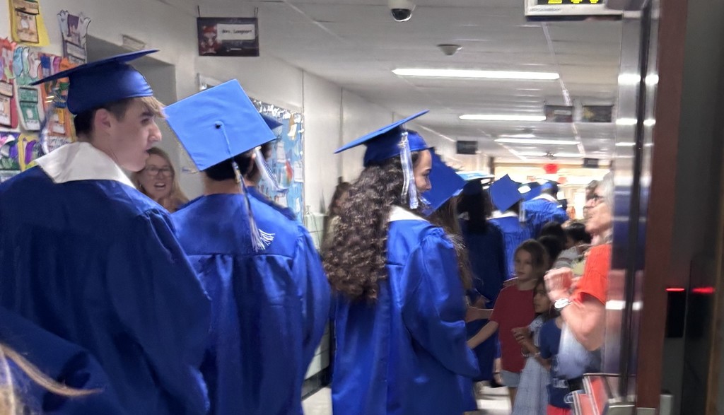 WHS 12th graders wear cap and gown as they walk thru clapout at elementary alma mater