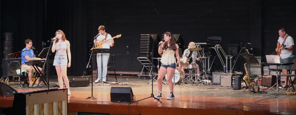 Two students singing with instructors playing back up instruments