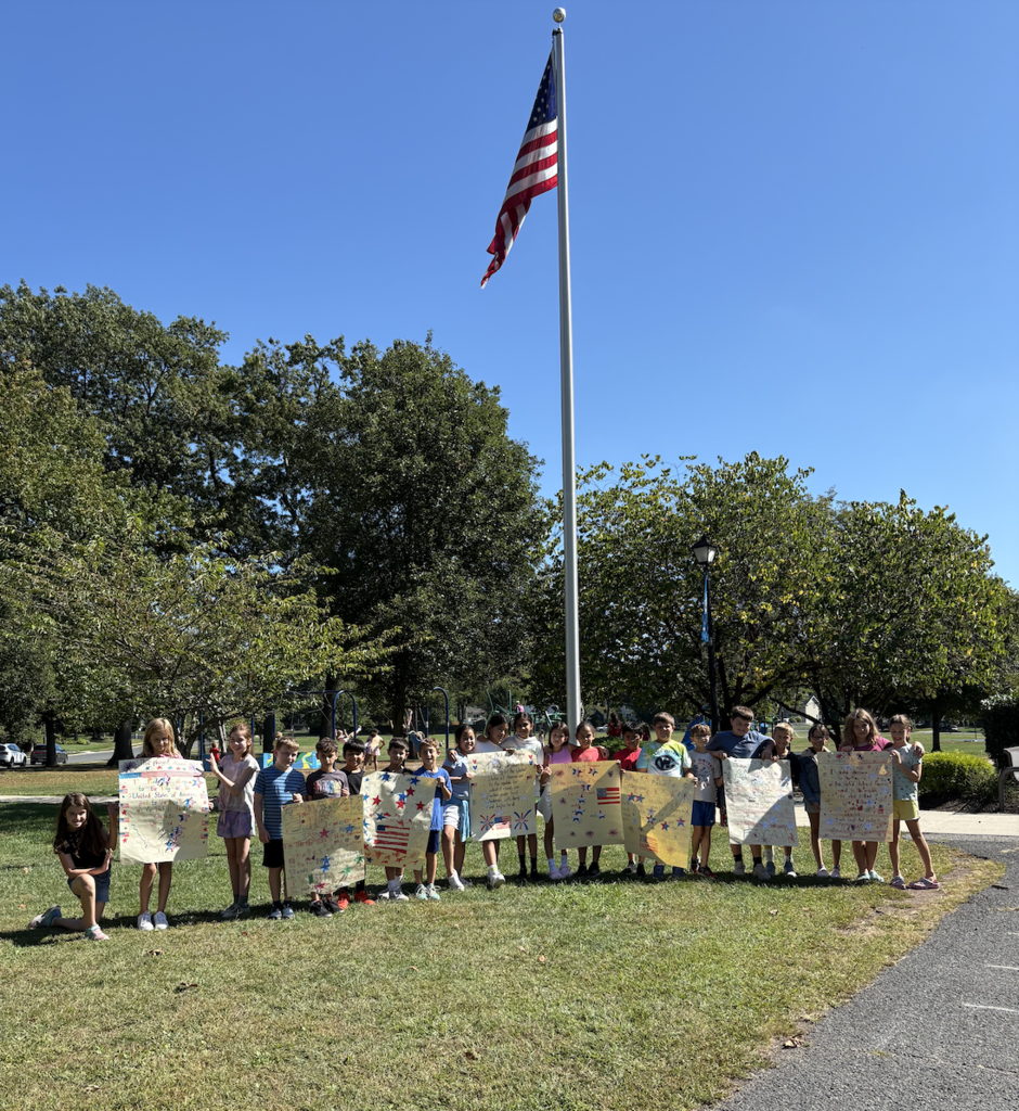 Students show their pride and stand with the American flag outside.