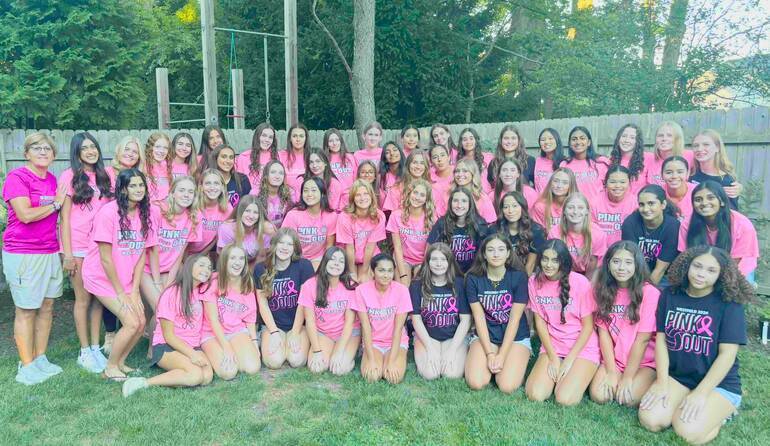Volleyball players in a yard wearing pink shirts