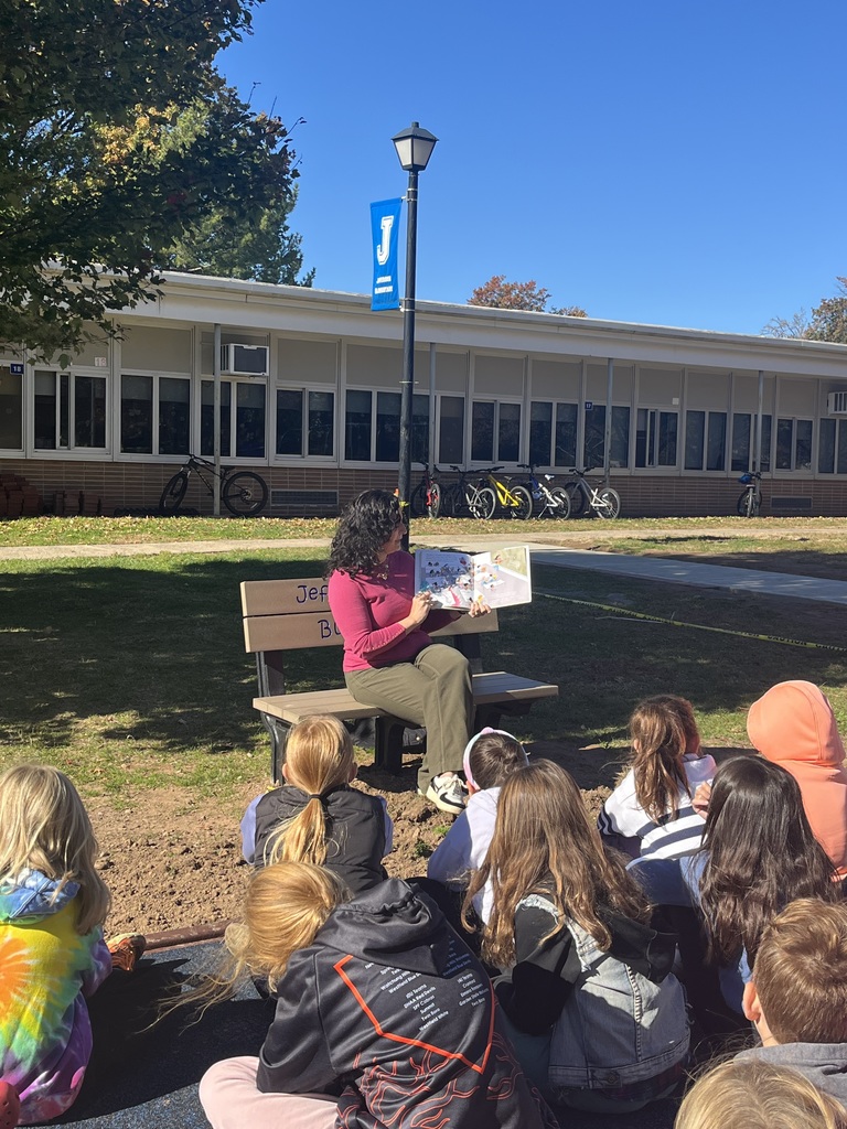 Director seated on the buddy bench and read the story to the students. 