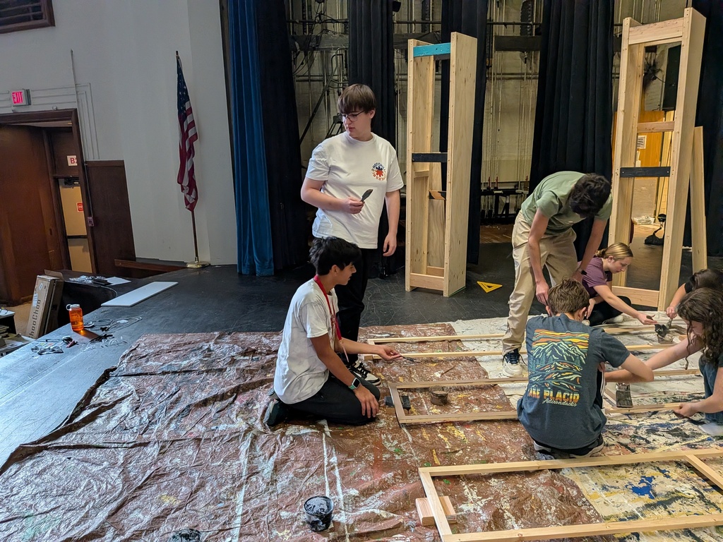 Students painting set on stage.