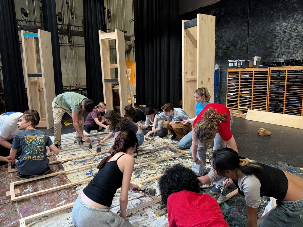 Students painting set on stage.